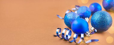 Kahverengi arka planda mavi taşaklardan yılbaşı kartı. Noel kompozisyonu. Pankart, kartpostal. Yakın plan. Boşluğu kopyala.