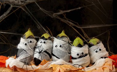 Cadılar Bayramı geçmişi. Tahta bir masanın üzerinde tıbbi bandajlara sarılı ürkütücü patlıcan. Cadılar Bayramı yemeği. Boşluğu kopyala.