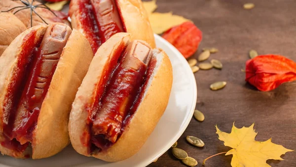 Halloween food. Halloween hot dog. Bloody fingers from sausages in rolls with ketchup. Scary food. Themed food. Dark wooden background.