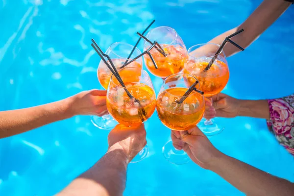 close up of cocktails in hands of people on blue background