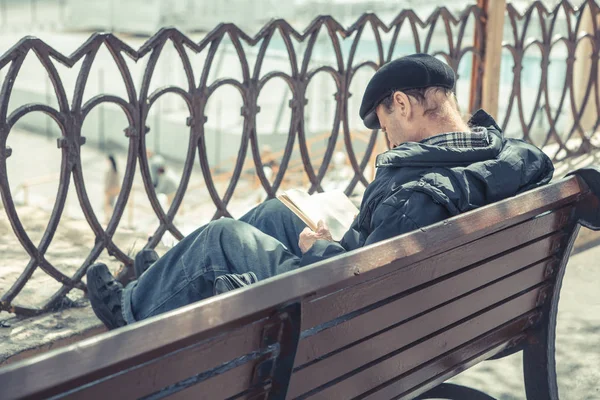 公園のベンチに座って本を読んでいる男は — ストック写真