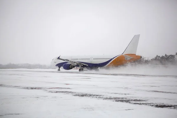 在暴风雪期间 现代双引擎客机在机场滑行 — 图库照片