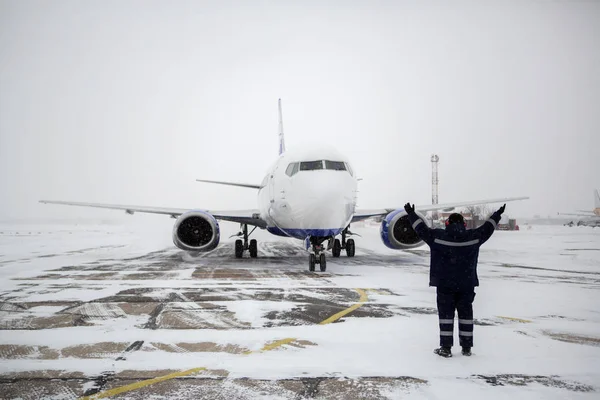 在暴风雪中 在机场停机坪上停放现代客机的地面机组人员成员 — 图库照片