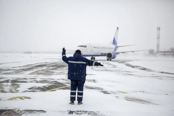 在暴风雪中 在机场停机坪上停放现代客机的地面机组人员成员 — 图库照片
