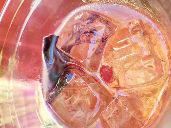 Güneş ışığında pembe buzlu kokteyl. buz küpleri üzerinde bulanık parlama. cam üst görünümü