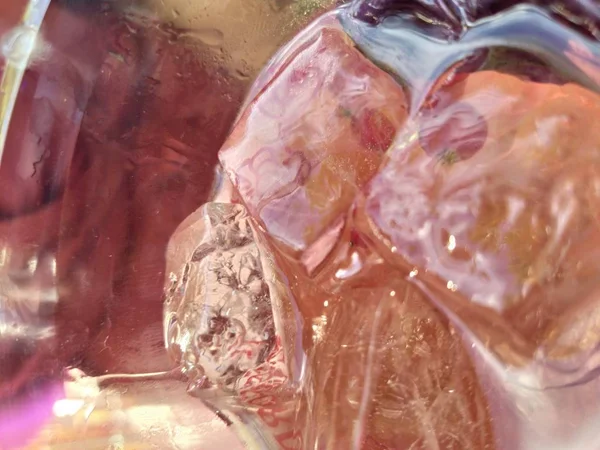 Güneş ışığında pembe buzlu kokteyl. buz küpleri üzerinde bulanık parlama. cam üst görünümü