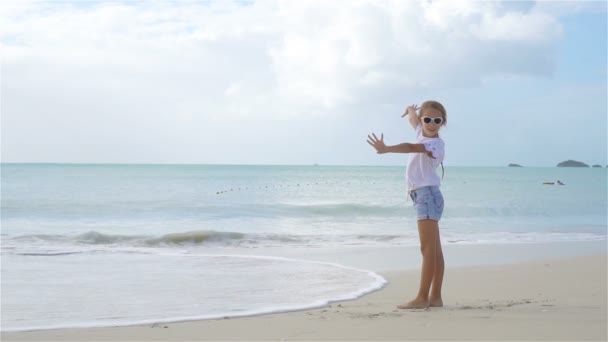 Aktywna mała dziewczynka na plaży mając dużo zabawy. — Wideo stockowe