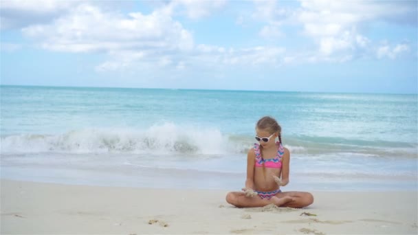 Aranyos kislány, fehér homokos strandján fekvő — Stock videók