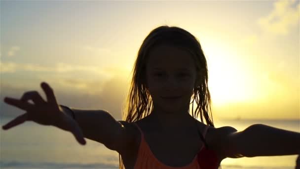 Entzückend glückliches kleines Mädchen am weißen Strand bei Sonnenuntergang. — Stockvideo