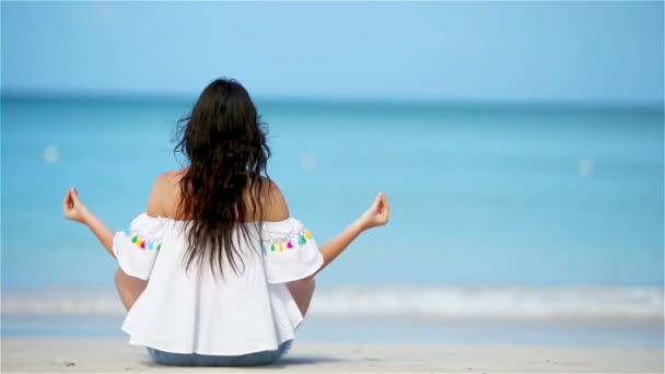 Vacker flicka i yoga position under tropiska semester. Friska unga kvinna som sitter i yoga position mediterar på stranden — Stockvideo
