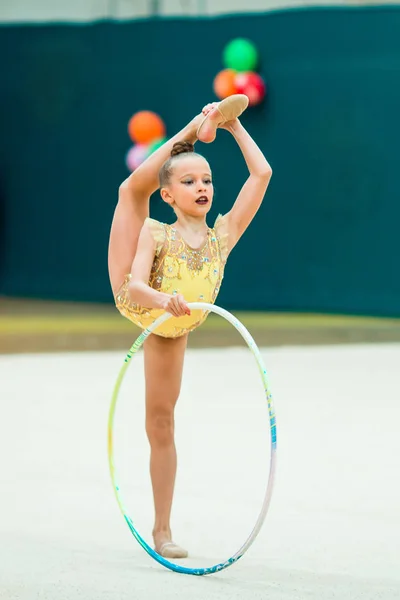 Beautiful little active gymnast girl with her performance on the carpet