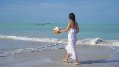 Genç ve güzel bir kadın beyaz kumsalda.