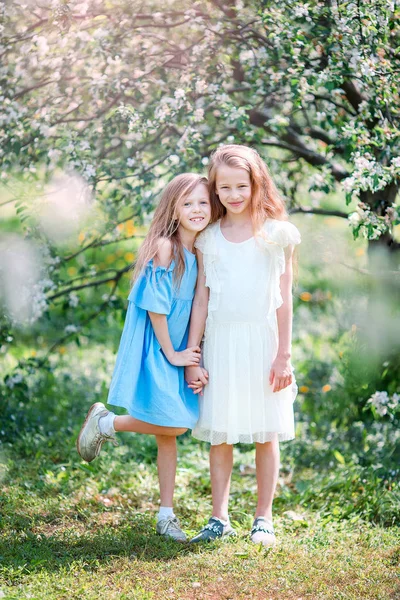 Чарівні маленькі дівчата в квітучому саду яблуні на весняний день — стокове фото