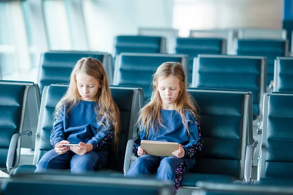 Pequenas garotas adoráveis no aeroporto à espera de embarque brincando com laptop — Fotografia de Stock
