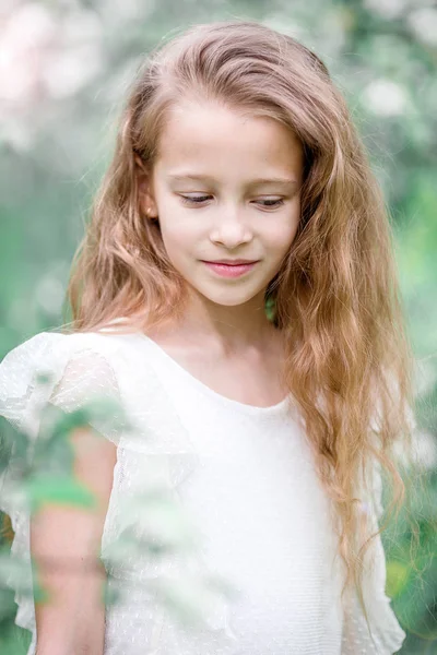 Прекрасная маленькая девочка в цветущем яблоневом саду в прекрасный весенний день — стоковое фото