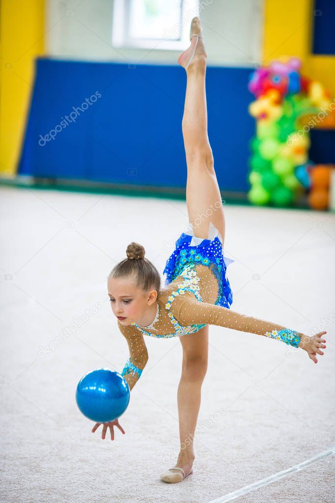 Beautiful little active gymnast girl with her performance on the carpet