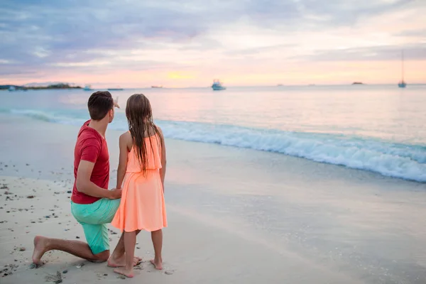年轻的父亲与他的小孩子看日落在异国情调的海滩上 — 图库照片
