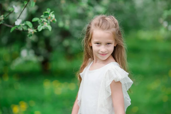 Adorable niña en el jardín de manzanas en flor en hermoso día de primavera —  Fotos de Stock