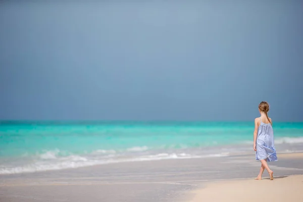 Krásná holčička v šatech na pláži baví. — Stock fotografie