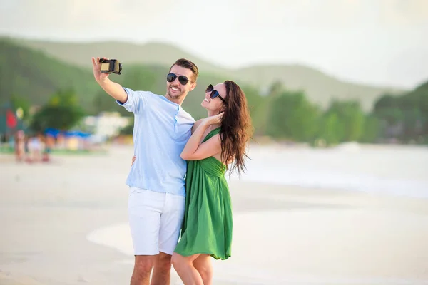 Balayı tatilinde beyaz sahilde fotoğraf çeken mutlu çift. — Stok fotoğraf