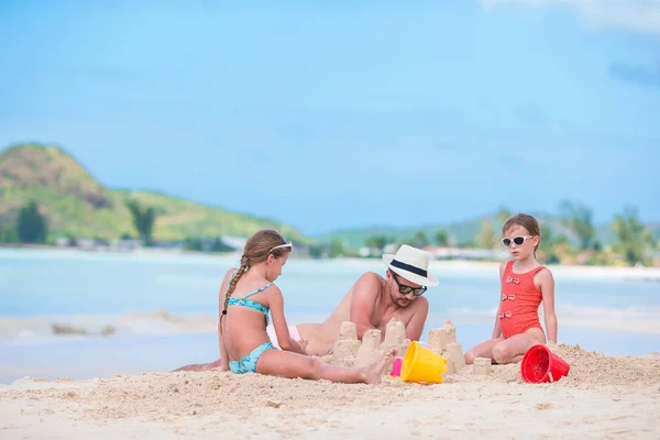 Família fazendo castelo de areia na praia branca tropical — Fotografia de Stock