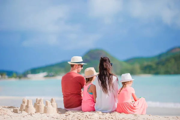 Familie van vier zandkasteel op tropica strand maken — Stockfoto