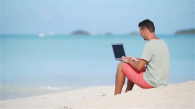 tropik sahil üstünde laptop ile genç adam.