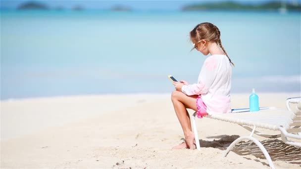 Little girl making video or photo with by her camera sitting on the sunbed — Stock Video