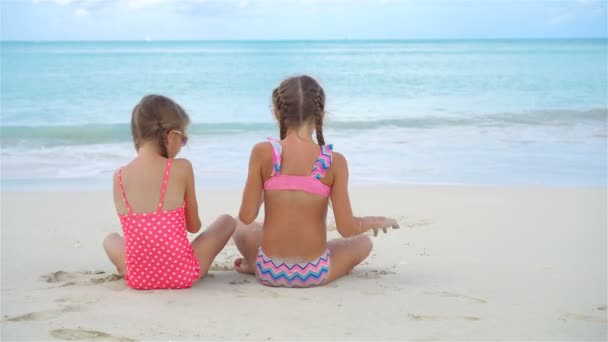 Két boldog kislány jól szórakozik a trópusi strandon, homokkal játszanak. — Stock videók