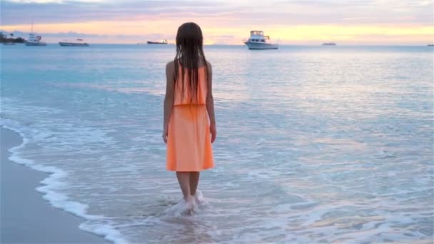 Silhouette eines kleinen Mädchens am Strand bei Sonnenuntergang. — Stockvideo