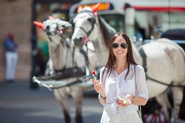 Tourist girl enjoying a stroll through Vienna and looking at the beautiful horses in the carriage clipart