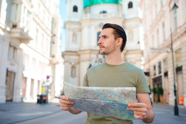 男子旅游城市地图与欧洲街的背包。看着地图的欧洲城市的白人男孩. — 图库照片