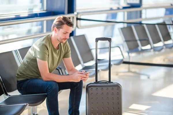 Passenger in a airport lounge waiting for flight aircraft. Young man with cellphone in airport waiting for landing — Stock Photo, Image