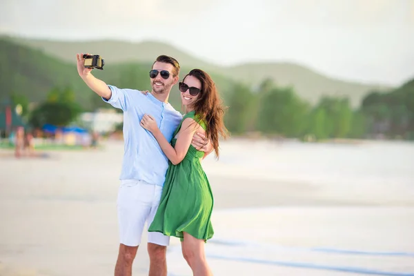 Pareja feliz tomando una foto en la playa blanca en las vacaciones de luna de miel — Foto de Stock