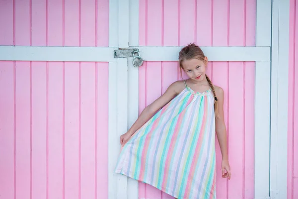 Pequeña linda chica de pie cerca de la pared de color brillante —  Fotos de Stock