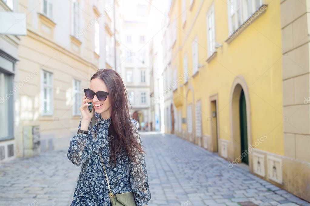 Woman talk by her smartphone in city. Young attractive tourist outdoors in italian city