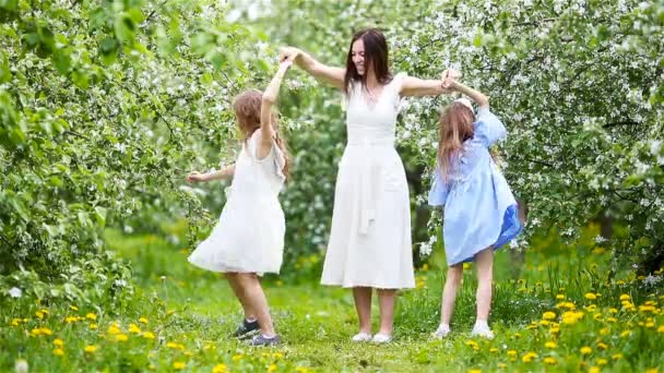 Adorables niñas con madre joven en el floreciente jardín de cerezos en el hermoso día de primavera — Vídeos de Stock