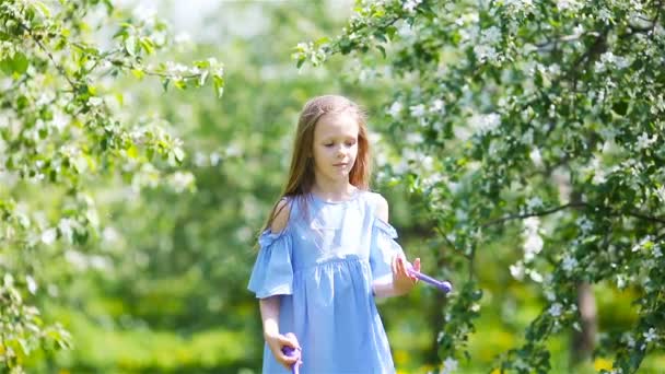 Чарівна маленька дівчинка в квітучому яблучному саду в красивий весняний день — стокове відео