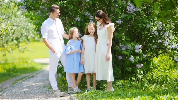 Familia de cuatro en el jardín floreciente en hermoso día de primavera — Vídeo de stock