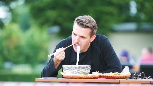 Šťastný Člověk Jíst Asijské Jídlo Klacky Venkovní Kavárně — Stock video