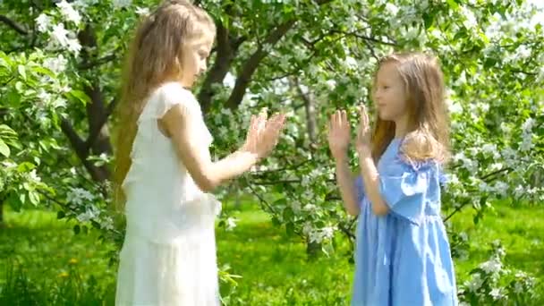 Adorables niñas en el jardín de manzanos en flor en el día de primavera — Vídeo de stock