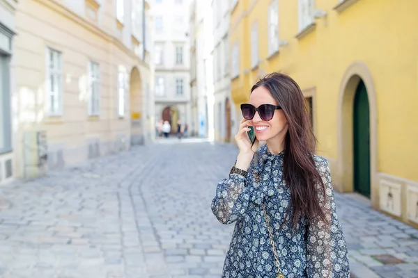 Woman talk by her smartphone in city. Young attractive tourist outdoors in italian city — Stock Photo, Image