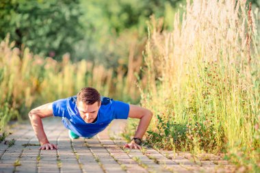Spor yaparken sportif genç adam açık havada parkta egzersizleri