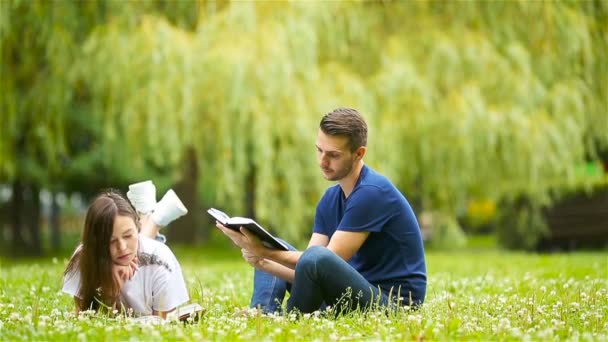 Ontspannen jong koppel lezingsboeken liggend op gras — Stockvideo