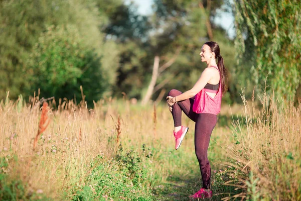 Jovem mulher sorrindo fazendo exercícios esportivos ao ar livre — Fotografia de Stock