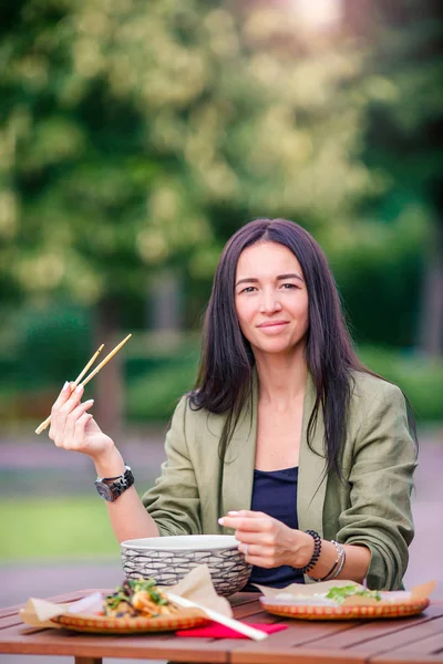 Młoda kobieta jedzenie wziąć od makaron na ulicy — Zdjęcie stockowe