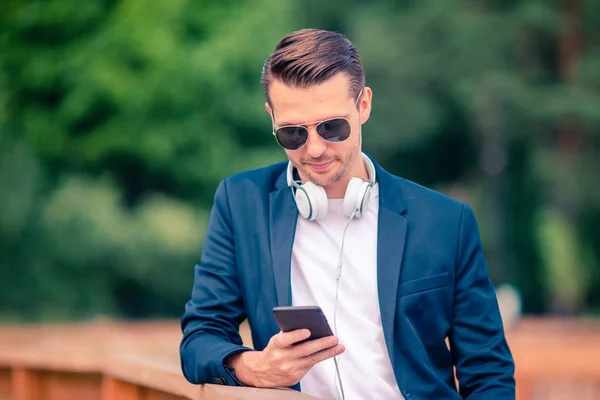 Człowiek jest czytanie wiadomości tekstowych na telefon komórkowy, podczas spaceru w parku — Zdjęcie stockowe