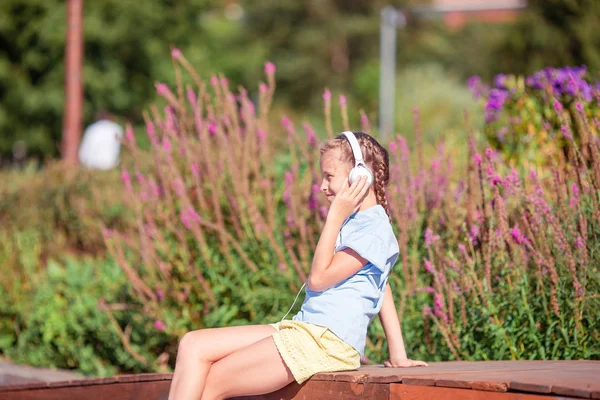 Pequena menina adorável ouvir música no parque — Fotografia de Stock