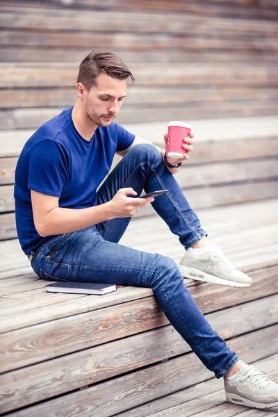L'homme lit un message texte sur son téléphone portable en marchant dans le parc — Photo