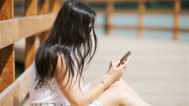 Şirin kadın parkta otururken cep telefonundan mesaj okuyor..